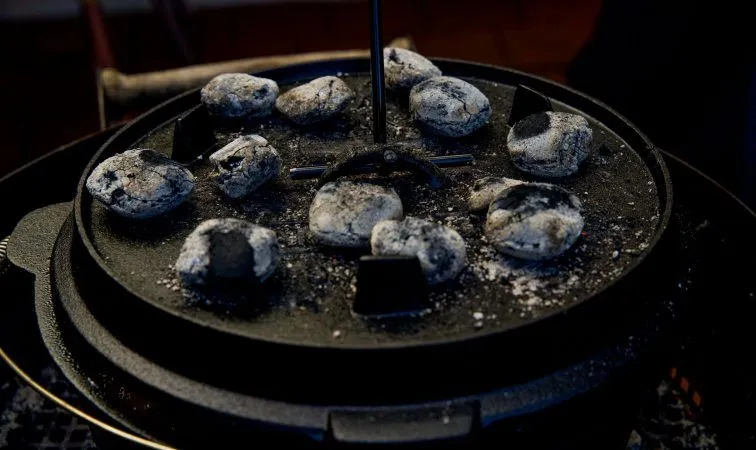 Glühende Briketts und Deckelheber auf Dutch Oven