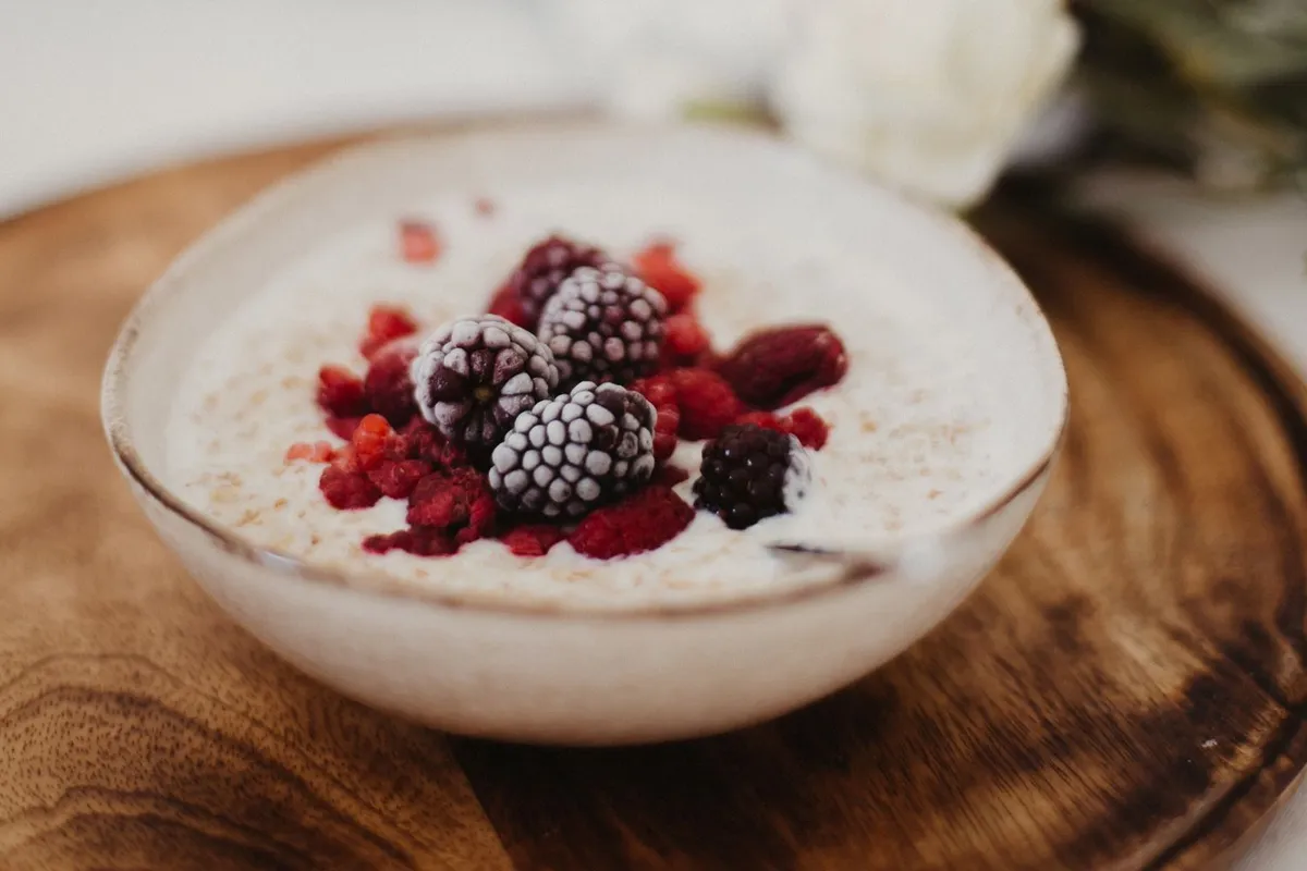 Joghurt mit Beeren in einer Schüssel auf einem Holzbrettchen
