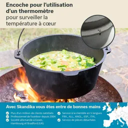 Ein gusseiserner Topf mit Suppe, der auf einem offenen Feuer steht. Im Hintergrund grüne Wiese.