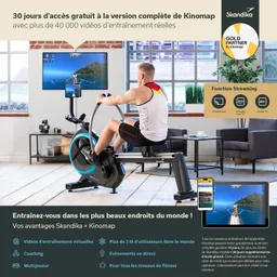 Ein Fitnessgerät mit einer Person, die darauf trainiert, ist vor einem Bildschirm platziert. Auf dem Bildschirm sind Landschaften mit einer Person beim Rudern zu sehen. Im Hintergrund sind Fenster mit Tageslicht und Möbel.