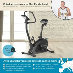 Schwarzes Fitnessgerät (Ergometer) in einem hellen Raum mit Holzfußboden und großen Fenstern, daneben eine Grafik über den Hersteller.
