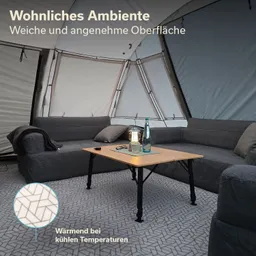 Gemütliche Sitzecke mit grauem Sofa, Tisch aus Holz und Wasserflaschen in einem Zelt mit strukturierter Bodenfläche.