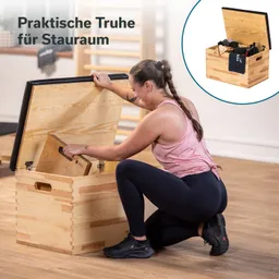 Holztruhe mit aufklappbarem Deckel, Person kniet neben der Truhe und greift ins Innere, Raum mit Holzboden.