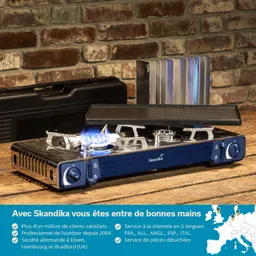 Gasherd mit Flamme auf einem Holzbrett, im Hintergrund eine Ziegelsteinwand und Zubehörteile.