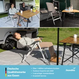 Zwei Personen sitzen an einem Tisch im Freien, über ihnen ein Zelt. Eine Person lehnt entspannt in einem Stuhl, die andere schaut lächelnd. Auf dem Tisch stehen Geschirr und Obst.
