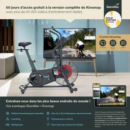 Fitness-Bike mit Windrad und Display, das Trainingsvideos zeigt. Im Hintergrund steht ein Fernseher, daneben ein Tablet.