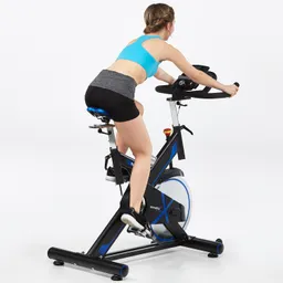 Person auf einem Fitness-Bike in sportlicher Kleidung, von hinten sichtbar, in neutralem Raum mit hellen Wänden.