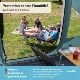 Familie im Freien, eine Person liegt entspannt auf einem Stuhl, während Kinder auf dem Boden spielen. Im Hintergrund sind Pflanzen sichtbar, ein Tisch mit Getränk und Buch.