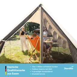 Zelt mit transparenten Seiten, in dem eine Person auf einem Stuhl sitzt. Zwei Personen stehen draußen, eine mit Getränk.
