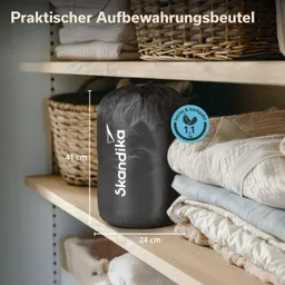 Schwarzer Aufbewahrungsbeutel mit Beschriftung "Skandika" auf einem Regal. Neben dem Beutel liegen mehrere faltbare Decken.