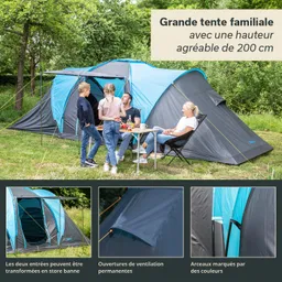 Familienzelt mit blauer und grauer Plane. Vier Personen stehen und sitzen vor einem Tisch im Freien, umgeben von Bäumen.
