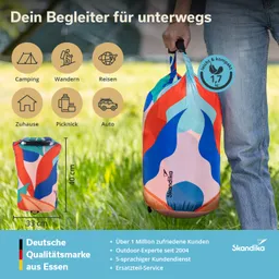 Bunte, zusammengerollte Tragetasche mit Grafikdesign, gehalten von einer Person in Jeans. Hintergrund mit Gras und Zelt.