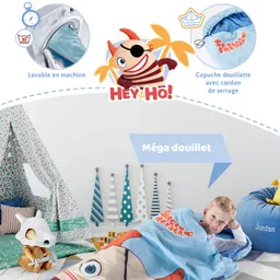 Das Bild zeigt ein farbenfrohes Kinderzimmer mit einem Schlafsack, dekorativen Bäumen und einem Zelt. Ein Kind liegt in einem blauen Schlafsack mit einem Spielzeug in der Hand.