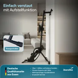 Fitnessgerät in schwarzer Farbe steht an einer Wand in einem modern eingerichteten Raum. Couch und Regale im Hintergrund sichtbar.