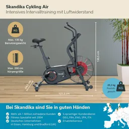 Fahrradtrainer Skandika mit Luftwiderstand, Maße und Gewichtsangaben, beige Wand im Hintergrund, Pflanze rechts.