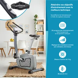 Ergometrie mit Bildschirm und verstellbarem Sattel in einem modernen Raum, umgeben von Möbeln und Pflanzen.