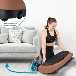 Eine Person kniet vor einem Möbelstück und hält ein Fitnessgerät in der Hand. Der Hintergrund zeigt ein graues Sofa mit Kissen und einem kleinen Pflanzenbehälter.