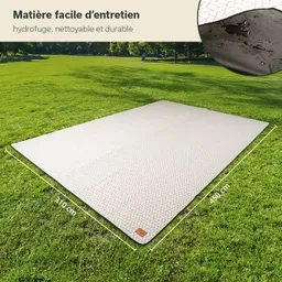 Eine große, rechteckige Matte mit einem geometrischen Muster liegt auf einer grünen Wiese. Die Mattenmaße sind 310 cm x 450 cm.