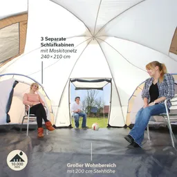 Zelt mit drei Schlafkabinen und großem Wohnbereich. Zwei Personen sitzen auf Stühlen, eine weitere Person sitzt im Hintergrund.