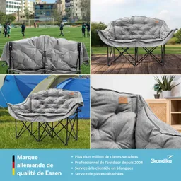 Das Bild zeigt ein graues Klappsofa mit weicher Polsterung, platziert auf Rasen und Holz. Im Hintergrund sind Menschen beim Fußballspielen zu sehen. Teile des Sofas sind detailliert abgebildet.