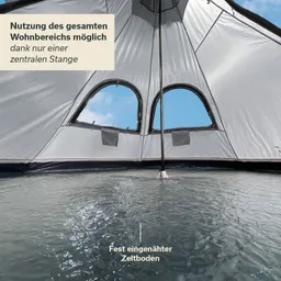 Innenansicht eines Zeltes mit grauem Stoff, zwei Fenstern und einer zentralen Stange. Zeltboden ist eingehängt und feucht.