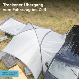 Zelt mit grauem Überdach, das an ein Fahrzeug anschließt. Im Vordergrund steht ein Tisch mit zwei Stühlen.