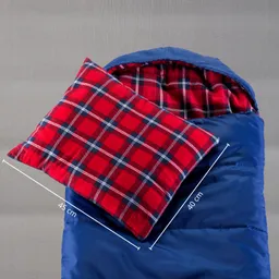 Ein blauer Schlafsack mit einem roten Kissen im Karomuster liegt auf einem grauen Hintergrund. Kissen und Schlafsack sind innen sichtbar.