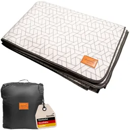 Fleece-Decke mit geometrischem Muster, zusammengefaltet und auf einer schwarzen Tragetasche mit Etikett.