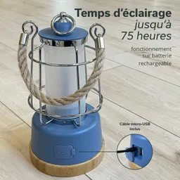 Eine blaue Laterne mit einem metallenen Schutzgitter, einem Seilgriff und einem Holzsockel. Micro-USB-Anschluss sichtbar.