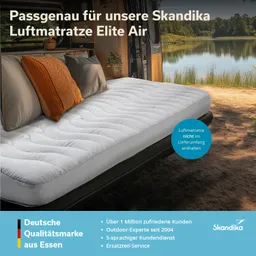 Luftmatratze auf einem Bett im Van, umgeben von Kissen, mit Blick auf eine idyllische Naturkulisse am Wasser.