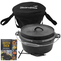 Dutch Oven aus Gusseisen mit Deckel und zwei Zubehörteilen, daneben ein schwarzer Tragetasche und ein Rezeptbuch mit Rezepten.
