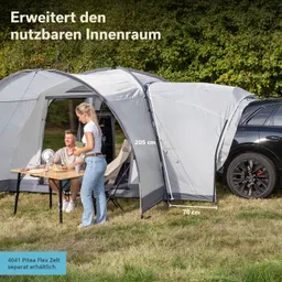Zelt mit grauem Stoff und seitlichem Anbau, zwei Personen am Tisch, Rasenfläche, Bäume im Hintergrund.