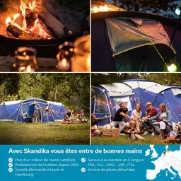 Lagerfeuer mit brennenden Holzscheiten, umgeben von mehreren Zelten im Freien. Gruppe von Personen sitzt zusammen, etwas spielend.