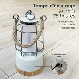 Eine tragbare Lampe mit einem weißen Korpus, umgeben von einem metallischen Gitter und einem Seilgriff. Die Basis ist aus hellem Holz. Textinformationen über die Beleuchtungsdauer und die Ladeoption sind sichtbar.