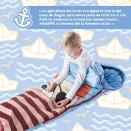 Ein Junge sitzt in einem bunten Schlafsack, der wie ein Tier aussieht, und zieht einen Reißverschluss. Der Hintergrund zeigt maritime Motive.