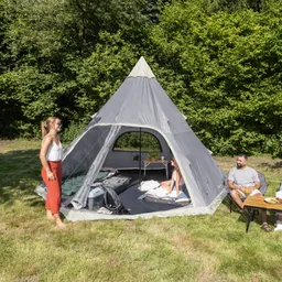 Zelt in Form eines Tipis, Personen sitzen am Tisch und stehen in der Nähe, umgeben von Grün und Wiese.