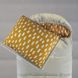 Eine beige Decke mit einem gepunkteten Inneren liegt zusammengefaltet. Ein orangefarbenes Kissen ist darauf platziert, mit blauen Muster. Maße sind angegeben.