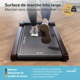 Laufband mit breiter Lauffläche. Die Abmessungen von 104 cm und 44 cm sind angegeben. Schuhe auf der Lauffläche sichtbar. Holzrahmen.