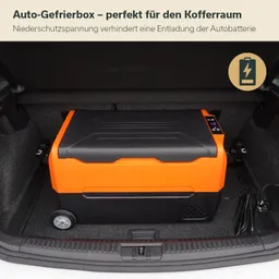 Eine orangefarbene Auto-Gefrierbox steht im Kofferraum eines Autos. Daneben befinden sich Kabel und Anschlüsse. Die Innenausstattung ist dunkel.