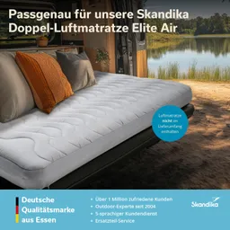 Doppel-Luftmatratze in einem Van mit zwei Kissen, Aussicht auf einen See und Wald im Hintergrund. Textinformationen im Bild.