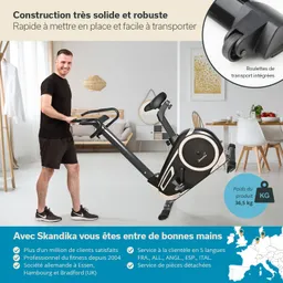 Ein Mann steht neben einem Fitnessgerät in einem modernen Raum. Das Gerät ist schwarz mit goldenen Akzenten und hat integrierte Transportrollen. Im Hintergrund sind Möbel und dekorative Elemente sichtbar.