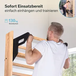 Mann mit kurzen Haaren zieht eine schwarze Vorrichtung an einer Holztrainerwand hoch. Die Wand hat sieben horizontale Sprossen.