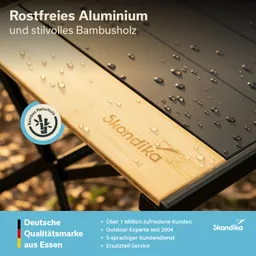 Tischplatte aus rostfreiem Aluminium und Bambusholz mit Regentropfen, Logo "Skandika" sichtbar.