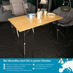 Holztisch mit zwei Tellern, Besteck und einer Thermoskanne. Im Hintergrund ein graues Sofa und ein Campingstuhl. Schwarzer Boden.