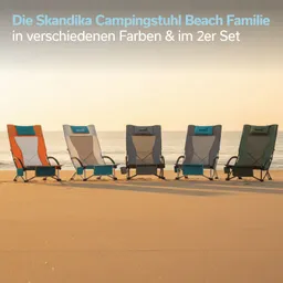 Fünf Campingstühle in unterschiedlichen Farben stehen nebeneinander am Strand. Der Sand und das Meer sind im Hintergrund sichtbar.