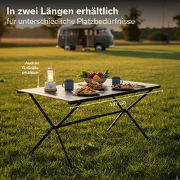 Ein Tisch mit verschiedenen Speisen und Getränken steht auf einer Wiese. Im Hintergrund ein Fahrzeug.