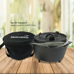 Schwarze Transporttasche mit Logo und ein gusseiserner Dutch Oven mit Deckel stehen auf einem Holztisch.
