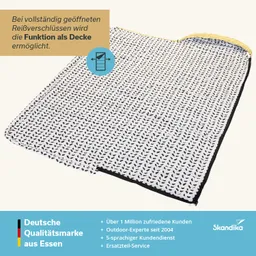 Eine Decke mit einem Muster aus kleinen Blättern in Schwarz auf Weiß, am Rand mit einem schwarzen und gelben Reißverschluss.