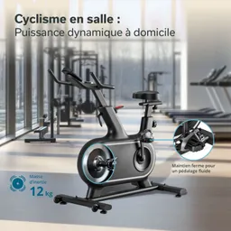 Indoor-Fahrrad mit grauem Rahmen in einem Fitnessstudio, im Hintergrund weitere Fitnessgeräte und große Fenster.