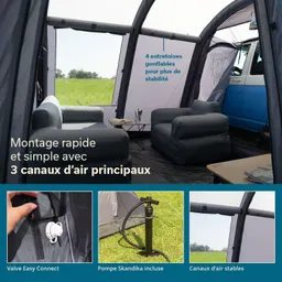 Innenraum eines Zeltes mit zwei grauen Sitzmöbeln, einem Tisch und einem blauen Fahrzeug im Hintergrund. Grüne Wiese außerhalb.